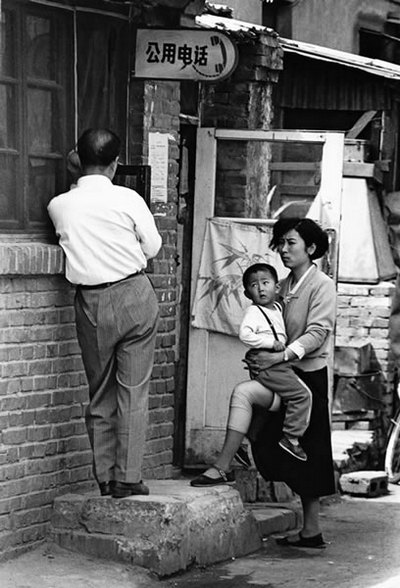 Женщина с ребёнком ждёт своей очереди возле общественного телефона. Фото: Великая Эпоха.