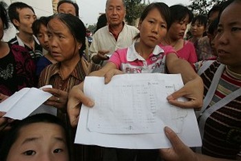 Родители пострадавших детей держат заключения врачей, подтверждающие отравление свинцом. Фото с epochtimes.com