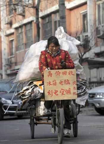 Женщина едет по одной из улиц Пекина на велосипеде, загруженном материалами для повторной переработки. Фото: Liu Jin /AFP /Getty Images