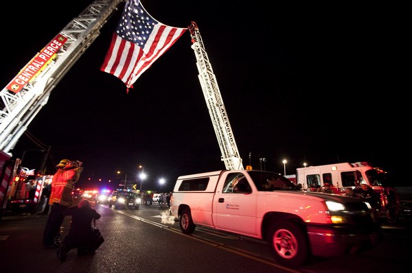 Пожарные поднимают гигантский флаг на автокране, чтобы чтить память четырех Лейквудских полицейских. Фото: Stephen Brashear/Getty Images)