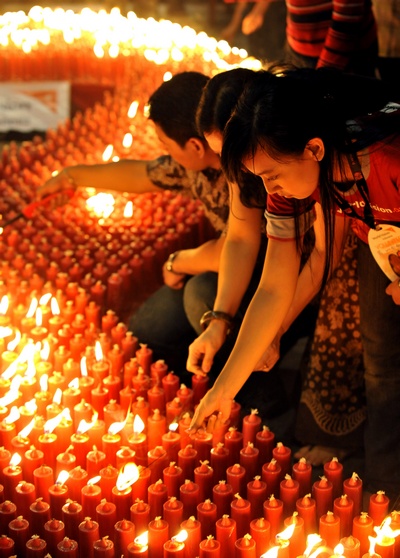 Всемирный день борьбы со СПИДом. Индонезийский доброволец зажигает свечи во время церемонии, чтобы отметить Мировой День борьбы со СПИДом в Джакарте 1 декабря 2009.  Фото: ADEK BERRY/AFP/Getty Images