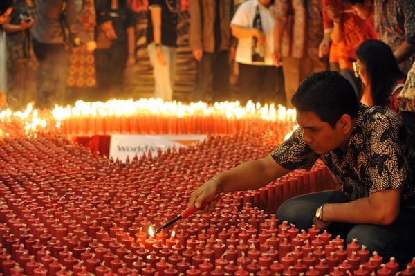 Всемирный день борьбы со СПИДом. Индонезийский доброволец зажигает свечи во время церемонии, чтобы отметить Мировой День борьбы со СПИДом в Джакарте 1 декабря 2009.  Фото: ADEK BERRY/AFP/Getty Images