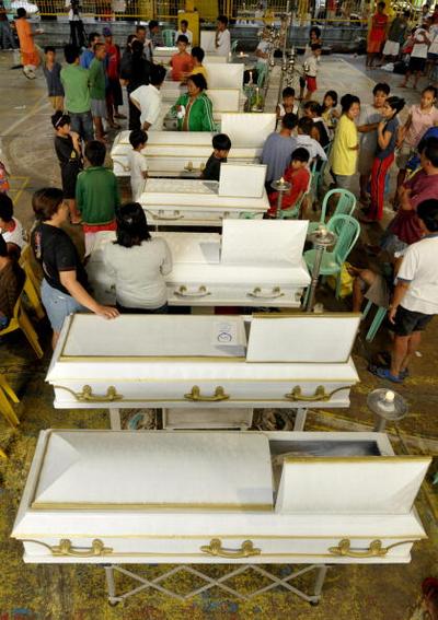Родственники около гробов жертв урагана Кетсан в Маниле (28.09.2009).  Фото: JAY DIRECTO/AFP/Getty Images
