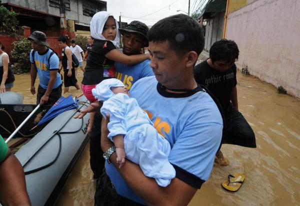 Спасатели переносят в лодку детей в городе Пассиг в Маниле (27.09ю2009). Фото:  MIKE CLARKE/AFP/Getty Images