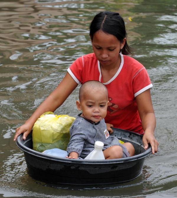 Мать перевозит своего ребёнка в городе Сан Педро в Маниле (30.09.2009). Фото: TED ALJIBE/AFP/Getty Images