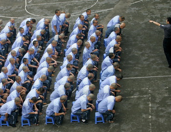 Заключённые слушают указания охранника в тюрьме Чунцина 30 мая 2005 года. Фото: China Photos/Getty Images