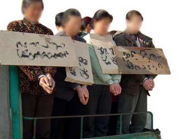 Разжигание ненависти. Последователей Фалуньгун возят по улицам в наручниках с  табличками их имен на груди. Фото с minghui.com