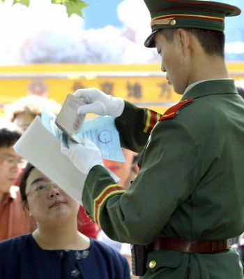Фото : Китайская военизированная охрана проверяет паспорт американского гражданина, претендующего на получение визы, Пекин, 17 мая 2004 года. (Goh Chai Hin/Getty Images)