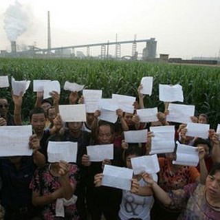 Жители деревни на фоне завода держат медицинские заключения, подтверждающие отравление свинцом. Провинция Хунань. 2009 год. Фото: Sound Of Hope