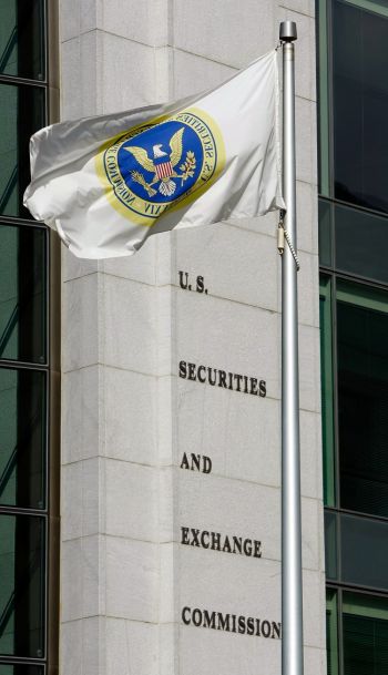 Флаг развевается перед американским зданием Комиссии по ценным бумагам и биржам в Вашингтоне (SEC). В 2011 году SEC приостановила торги некоторых китайских компаний, вышедших на биржу после обратного слияния, так как они искажали предоставляемую информацию. (Chip Somodevilla/Getty Images)