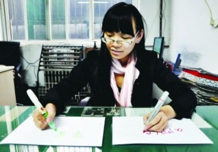 Чэнь Сыюань одновременно пишет слово «яблоко» правой рукой на китайской языке, а левой – на английском. Фото: secretchina.com