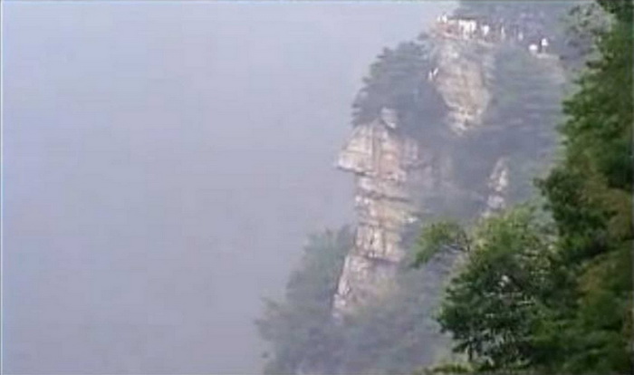 Гигантское каменное лицо с пышными волосами из сосен расположено на горе Лушань