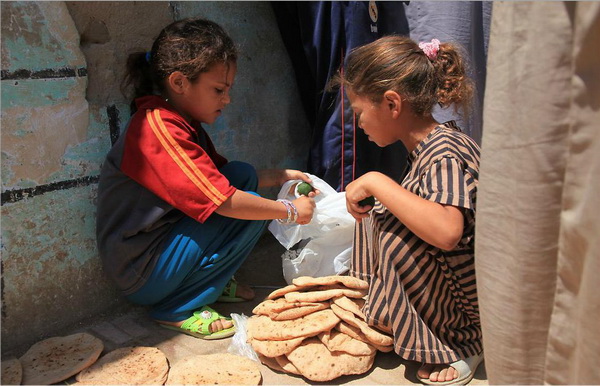 Местные девочки в оазисе Эль Бахарая положили остужать на землю только что купленный хлеб. Фото: Яйра Ясмин/Великая Эпоха