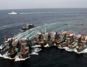 Снимок  16 ноября 2011 года показывает нелегальные китайские рыболовные суда, преследуемые вертолётом береговой охраны и коммандос на резиновых лодках в южнокорейских водах. Фото: Dong-a Ilbo/AFP/Getty Images