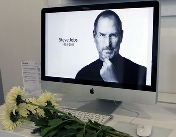 Цветы перед портретом основателя и экс-главы компании Apple Стива Джобса в магазине re:Store. Фото РИА Новости