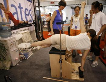 17 июля 2006 года женщина тестирует тренажер для выполнения упражнений пилатес на фитнесс-выставке в Пекине. Фото: Frederic J. Brown/AFP/Getty Images