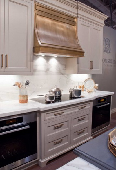 Эта кухня представляет сочетание мягких золотых акцентов с элементами из серебра и нержавеющей стали, два оттенка мягкого серого цвета, дерево и белый мрамор. Фото: Bloomsbury Fine Cabinetry