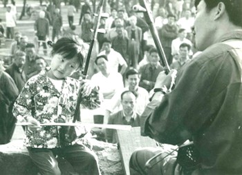 Когда Ци Сяочунь было шесть лет, отец научил ee играть на эрху, они играли с ним ежедневно. Во время репетиций они часто были окружены толпой людей, которая часами слушала музыку, отбивая такт руками и ногами. Фото Epoch Times