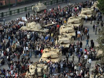 Колонна танков Abrams выстраивается в ряд вдоль улицы, в то время как египетские демонстранты собираются на площади Тахрир в Каире 30 января 2011 года, на шестой день акций протеста против режима Хосни Мубарака. (Мигель Медина / AFP / Getty Images) 