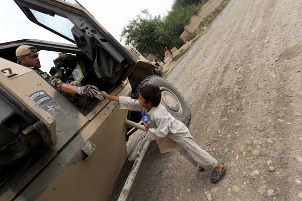 Пехотинец дает пакетик печенья и бутылку воды афганскому ребенку. Фото: Miguel Villagran/Getty Images