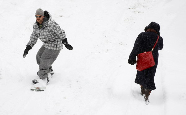 Зимой не до скуки. Сноубордист и прохожая в центре Эшвилля, штат Северная Каролина, 10 января. Фото: Scott Halleran/Getty Images