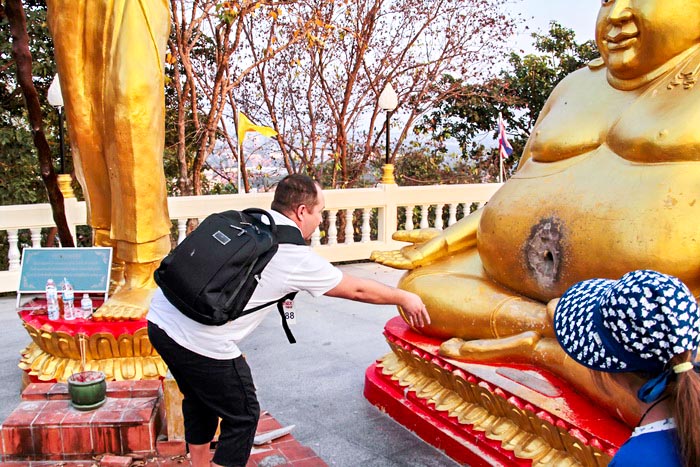 Мужчина пытается попасть монеткой в отверстие статуи Будды. Отдых в Паттайя. Фото: Николай Карпов/Великая Эпоха (The Epoch Times)