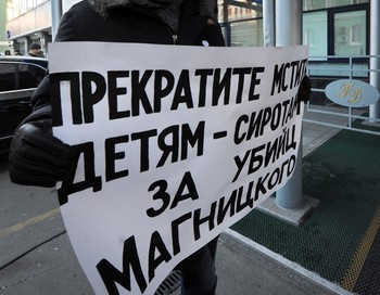 Плакат против принятия закона о запрете усыновления американцами российских детей держит лидер оппозиции Борис Немцов у здания Госдумы, 19 декабря 2012 года. Фото: ANDREY SMIRNOV/AFP/Getty Images
