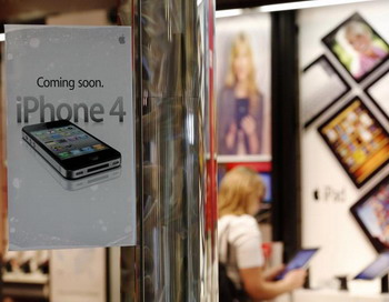 Покупательница в магазине Verizon рассматривает Apple iPad, на стекле рекламка о скором выходе Verizon iPhone. 3 февраля 2011, Орем, штат Юта, США. Фото: George Frey/Getty Images