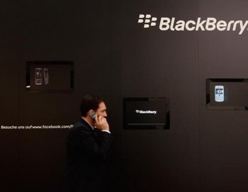 Говорящий по сотовому телефону посетитель технологической ярмарки CeBIT, проходит мимо стенда Blackberry. CeBIT 2011 проходила с 1 по 5 марта 2011 в Ганновере (Германия). Фото: Sean Gallup/Getty Images