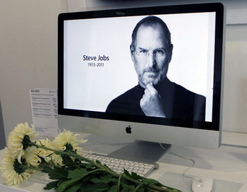 Цветы перед портретом основателя и экс-главы компании Apple Стива Джобса в магазине re:Store. Фото РИА Новости