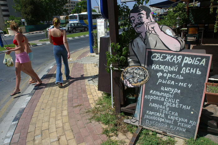 Туристы проходят мимо меню на русском языке, размещённого рядом с рестораном в Лимассоле. фото: LAURA BOUSHNAK/AFP/GettyImages