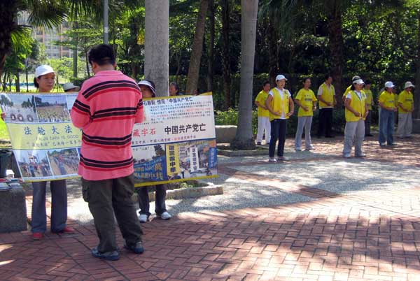 Китайский турист читает плaкат последователей Фалуньгун. Справа - демонстрация упражнений Фалуньгун. Фото: Великая Эпоха