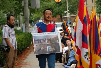 Житель Тибета  выступает с акцией протеста перед китайским консульством в Торонто. У него в руках фотографии жителей Тибета, погибших от разрывных пуль.  Фото: Мэтью Литл/ Великая Эпоха