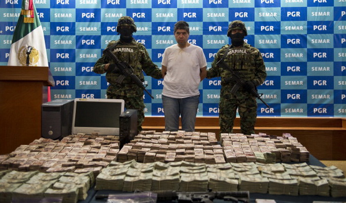 Мексиканские морские пехотинцы представляют прессе предполагаемого члена наркокартеля «Зетас» Эрика Йован Лосано Диаса, и деньги, изъятые во время его ареста в Мехико, 15 июня 2012 года. Фото: Ronaldo Schemidt/AFP/GettyImages