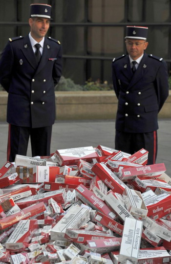 Офицеры таможни стоят около груды поддельных сигарет, изъятых и выложенных перед Министерством  финансов 22 апреля в Париже, Франция. Фото: Паскаль Ле СЕГРЕТЭН/ Getty Images 