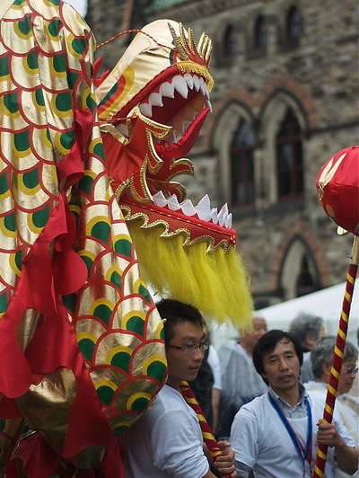 Китайцы, приветствующие Ху Цзиньтао, держат в руках куклы китайских драконов, которые используются в танцах. Фото: Matthew Little/Великая Эпоха/The Epoch Times
