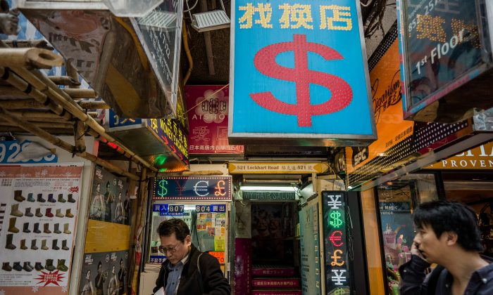 Мужчина (слева) выходит из пункта обмена валюты в Гонконге 22 ноября 2012 г. (Philippe Lopez / AFP / Getty Images) | Epoch Times Россия