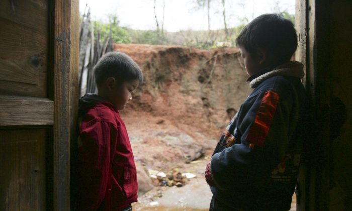 Двое детей, у которых подтверждено отравление свинцом, стоят в своем доме 16 марта 2007 года в уезде Часянь провинции Хунань, Китай. Было подтверждено, что около 100 человек из четырех деревень, большинство из которых дети, страдают от отравления свинцом в результате работы ближайшего плавильного завода, который был закрыт после 12 лет эксплуатации. Совсем недавно более 300 детей в городе Дапу округа Хэндун провинции Хунань показали высокий уровень свинца в крови. Мэр города говорит, что они грызли карандаши, это не химический завод в городе. (China Photos / Getty Images) | Epoch Times Россия