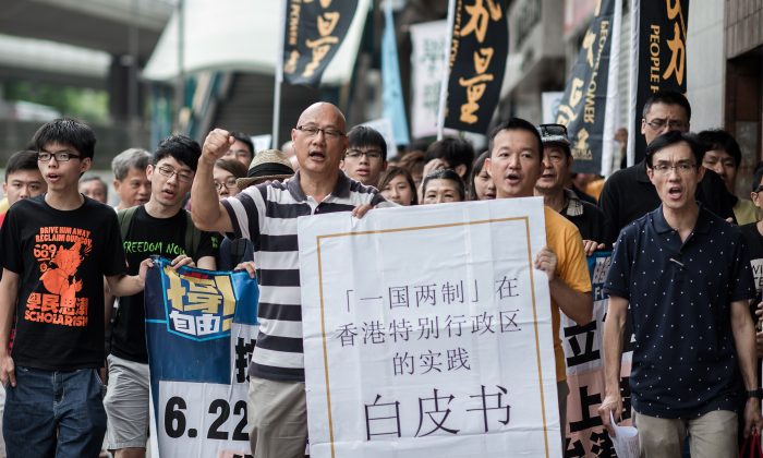 Демонстранты выкрикивают лозунги, держа в руках большую копию белой книги Пекина, маршируя к представительству Пекина в Гонконге 11 июня. Китай выпустил во вторник официальный документ, в котором подчеркивается, что он контролирует Гонконг. (Филипп Лопес / AFP / Getty Images) | Epoch Times Россия