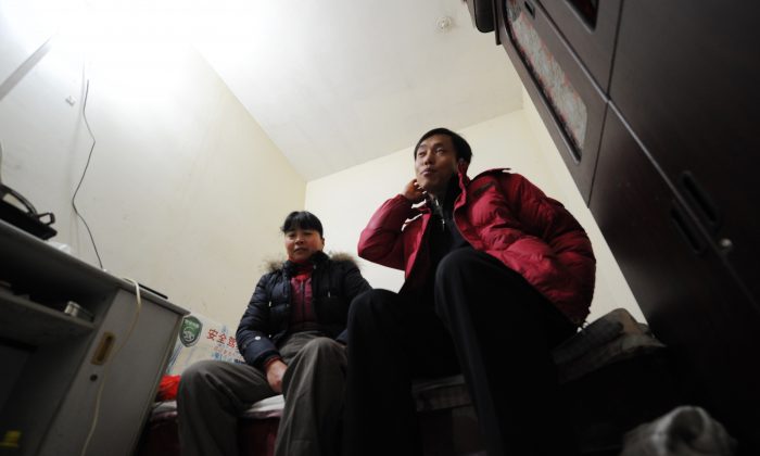 Китайские рабочие-мигранты сидят в своей крошечной комнате на трех этажах ниже в тускло освещенном бомбоубежище в Пекине. Эти рабочие принадлежат к тому, что жители Пекина теперь называют «крысиным племенем». (Питер Паркс / AFP / Getty Images) | Epoch Times Россия