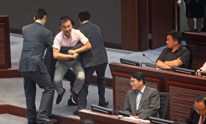 Член LegCo Рэймонд Чан Чи-чуен приведен в исполнение охранниками после протеста против правительственных отчетов, которые, по его мнению, не совсем точно отражают требование граждан Гонконга о выдвижении в гражданские права 15 июля 2014 г. (Epoch Times) | Epoch Times Россия