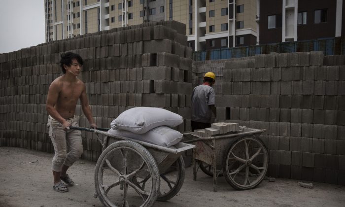 Китайский строитель толкает бетонную смесь на строительной площадке нового жилого комплекса 29 августа 2014 года в Пекине, Китай. Раздувание пузыря на рынке жилья способствует снижению экономических показателей Китая. (Кевин Фрайер / Getty Images) | Epoch Times Россия