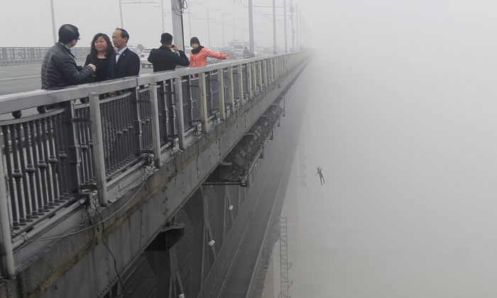 Молодой человек прыгает с моста через реку Янцзы в Ухане, Китай, в реку вслед за другим человеком, который совершил самоубийство за несколько минут до этого 27 февраля 2013 года. Полиция сообщила, что у них мало шансов выжить, и один из этих двоих был молодым мужчина, родившийся в мае 1993 г. (STR / AFP / Getty Images) | Epoch Times Россия