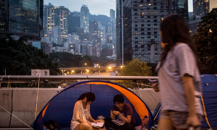 Активисты, выступающие за демократию, читают в палатке на улице возле правительственного комплекса Гонконга 26 октября 2014 года в Адмиралтейском районе Гонконга. Студенту-члену Hong Kong Scholarism было отказано во въезде на таможню в городе Шэньчжэнь, который граничит с Гонконгом, 7 ноября 2014 г. (Крис МакГрат / Getty Images) | Epoch Times Россия