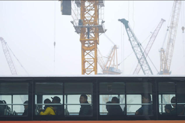 Автобус проезжает мимо стройки в Пекине 20 ноября 2014 года. Фото: WANG ZHAO/AFP/Getty Images | Epoch Times Россия