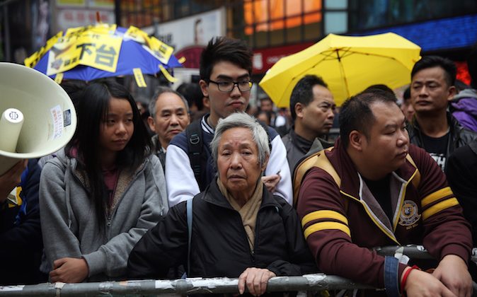 Протестующие наблюдают за пределами площадки демократического протеста, как полиция очищает территорию в районе Козуэй-Бэй в Гонконге 15 декабря 2014 г. (Исаак Лоуренс / AFP / Getty Images) | Epoch Times Россия