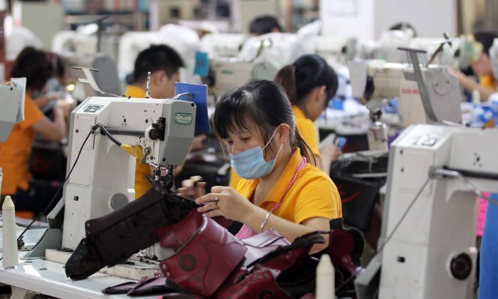 Рабочие работают на обувной фабрике в Цзиньцзяне, провинция Фуцзянь на юге Китая, 17 сентября 2013 г. (STR / AFP / Getty Images) | Epoch Times Россия