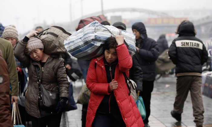 Рабочие-мигранты прибывают на вокзал Пекина с багажом 31 января 2013 года в Пекине, Китай. Министерство общественной безопасности, агентство при Госсовете, объявило о плане отмены «временного» вида на жительство в Китае. (Линтао Чжан / Getty Images) | Epoch Times Россия