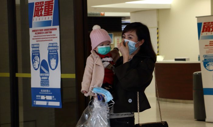 Женщина держит ребенка, надевая маску в больнице Королевы Марии 5 февраля. (Кири Чой / Epoch Times) | Epoch Times Россия