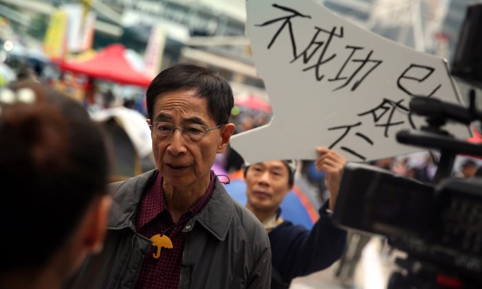 Мартин Ли (второй слева), председатель-основатель Демократической партии в Гонконге, дает интервью средствам массовой информации, в то время как протестующий (позади) держит знак поддержки на главном демократическом участке протеста в Адмиралтейском районе Гонконга. 11 декабря 2014 г. (Исаак Лоуренс / AFP / Getty Images) | Epoch Times Россия